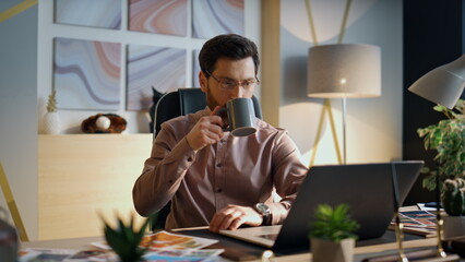 Wall Mural - Busy manager drinking coffee at office work close up. Worker looking at laptop.