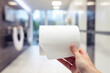 A close-up of a hand holding a toilet roll against a bright domestic background, emphasizing essential hygiene during uncertain times.