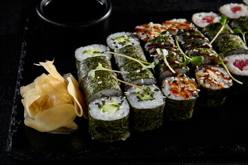 Poster - Assorted hosomaki sushi set with salmon, tuna, eel, and cucumber on black textured background