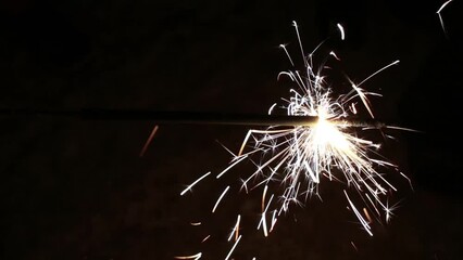 Wall Mural - Person is holding burning stick of sparkler at night.