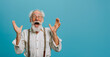 Old hoary man wearing glasses over isolated blue background. Crazy and scared with hands on head, afraid and surprised of shock with open mouth Closeup photo of excited crazy attractive grandpa 