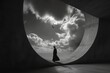 Conceptual image with a silhouette of a woman in a long black dress against the backdrop of the sky and clouds. 
