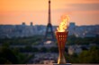 The olympic torch with flame in front of the Eiffel tower. Symbol of The Olympic Games on blurred background. Winning and victory concept