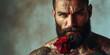 A tattooed muscular bearded man, romantic emotivity, is holding a rose in his hand