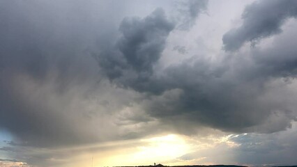 Wall Mural - time laps dramatic dark clouds approach sunlight at sunset time creating powerful movement in the ai