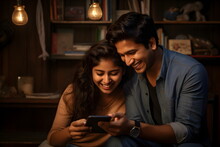 young indian couple using mobile phone at home