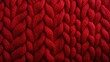  a close up view of a red knitted blanket with a large braiding pattern on the top of it.