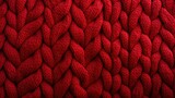  a close up view of a red knitted blanket with a large braiding pattern on the top of it.