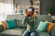 © Zamrznuti tonovi - Young woman using virtual reality headset at home while sitting on a sofa