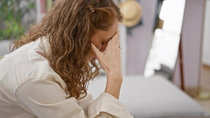 Poster - Stressed young woman sitting alone on sofa at home, embodying sadness and frustration amidst her personal conflict and depression