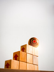 Poster - Big target icon on wooden sphere on top of cube blocks bar graph chart steps with up arrows symbol on white vertical background. Investment, income, revenue, profit goal, business growth concepts.
