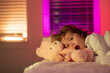 Cute drowsy sleepy child with toy teddy bear in bed, bedtime, childhood and growth kids concept, close-up indoor portrait. Child is afraid of the dark. Nightmares and terrible dreams in children.