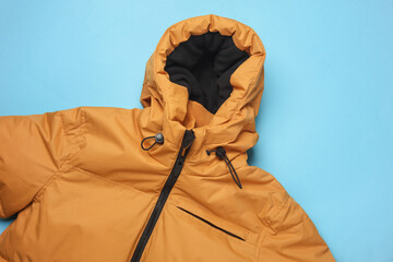 Yellow winter down jacket with hood on a blue background
