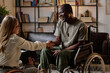 © AnnaStills - Joyful black veteran with disability shaking hand of his female therapist after successful session