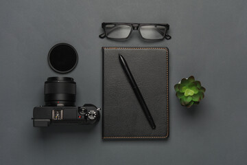 Creative layout with camera, notepad and accessories on black background