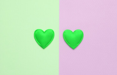 Wall Mural - Two green hearts on a blue-pink pastel background. Love concept