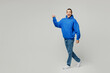 © ViDi Studio - Full body side view smiling happy young middle eastern man he wear blue hoody casual clothes walk go stroll point index finger aside isolated on plain solid white background studio. Lifestyle concept.