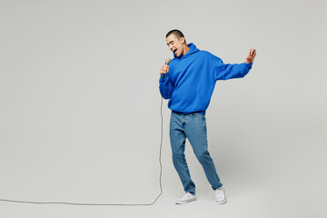 Wall Mural - Full body singer young middle eastern man wear blue hoody casual clothes sing song in microphone at karaoke club spread hand isolated on plain solid white background studio portrait Lifestyle concept