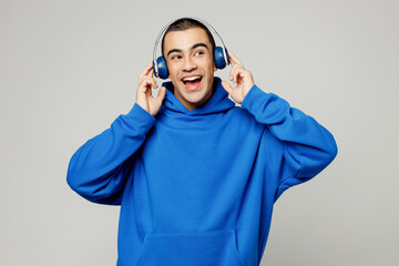 Wall Mural - Young smiling happy middle eastern man he wear blue hoody casual clothes listen to music in headphones look aside on area isolated on plain solid white background studio portrait. Lifestyle concept.