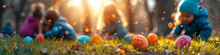 Colorful Easter Eggs On Grass With Children In The Background. Outdoor Easter Egg Hunt Concept With Copy Space. Springtime Holidays Design For Greeting Card, Postcard
