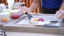 Cooking Rolled Ice Cream In Thai Style, Chopping Fruits On A Cold Pan. Ice Cream Vendor Makes The Portion Of Natural Fruit Ice Cream With Strawberries. Thai Style Stir-fried Rolled Ice Cream
