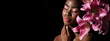 © Beauty Agent Studio - Pink colour lips. Beauty portrait of young African American model with art make up posing with lily blooming flowers isolated on black background.