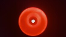 Directly Below Handheld Shot Of Circular Red Lamp Hanging In Dark Room