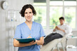 © JackF - Positive middle-aged woman doctor posing in doctor's cabinet with documents and pen in hands