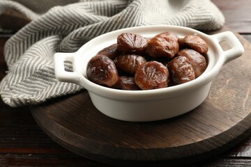 Wall Mural - Roasted edible sweet chestnuts in dish on light wooden table