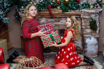 Wall Mural - Beautiful elegant girls near the Christmas tree in the New Year. Holiday. New Year. Children are models. Two sisters.