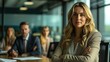 © CLOVER BACKGROUND - Female professional sitting in a boardroom with her team in the background