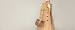 © Beauty Agent Studio - Autumn clothing shopping concept. Fashionable young model posing against grey background dressed in trench coat and holding stylish  bag.