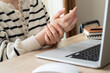 A woman has finger and hand pain after using a computer for a long time. Pain in wrist while using laptop, carpal tunnel syndrome.