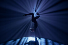 Female Gymnast On Dark Background Of Studio With Backlight. Acrobatic Girl Performing Handstand. Modern Choreography And Acrobatics Creative Advertising Concept.