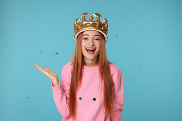 Poster - Beautiful young woman with inflatable crown under falling confetti on light blue background