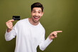 © deagreez - Portrait of astonished nice man hand hold debit card direct finger empty space isolated on khaki color background
