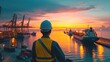 Backview of an engineer in orange safety vest and hard hat at busy port full with ships and containers at sunset or dawn