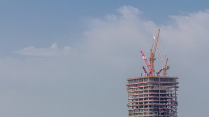 Wall Mural - Tower cranes working on the construction site of new skyscraper high-rise building aerial timelapse. Dubai