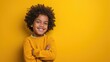 A boy with curly hair in a yellow sweater on a yellow background. Studio photo of a smiling child 6, 7, 8 years old. Free space