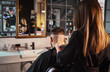Young female barber making men's undercut haircut hairstyle using Haircut Clipper opposite mirror Modern style barber shop. Haircare service local small business, cosmetics and personal care industry.