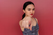 A displeased young asian woman calling out someone, gesturing with her finger. Isolated on a red background.
