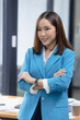 © SOMKID - Happy asian businesswoman standing with arms crossed in the office.