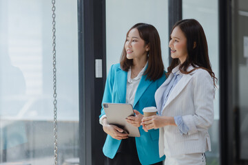 Happy excited two asian businesswoman working with tablet computer at office desk, Happy young woman overjoyed.