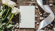 Vertical blank card near white decorations, pebbles and silk ribbons top view, wedding menu mockup