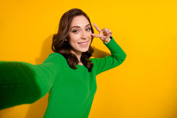 Wall Mural - Selfie photo of young charming brunette curly haired girlfriend show v sign posing like a star blogger isolated on yellow color background