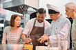 © LIGHTFIELD STUDIOS - good looking african american man learning how to use silicone brush next to chef and his friends