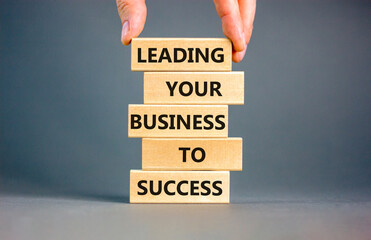 Wall Mural - Leading your business to success symbol. Concept words Leading your business to success on wooden blocks. Beautiful grey table grey background. Leading your business to success concept. Copy space.