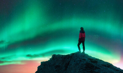 Wall Mural - Northern lights and woman on mountain peak at night. Aurora