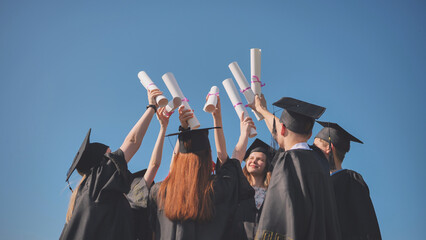 Wall Mural - College graduates with caps tie their diplomas together.