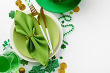 Table Blessings: St. Patrick's Day Festivity Arrangements. Top View Photo Of Plates, Cutlery, Pint Of Green Beer, Green Napkin Traditional Decor On White Background With Space For Advert Or Text